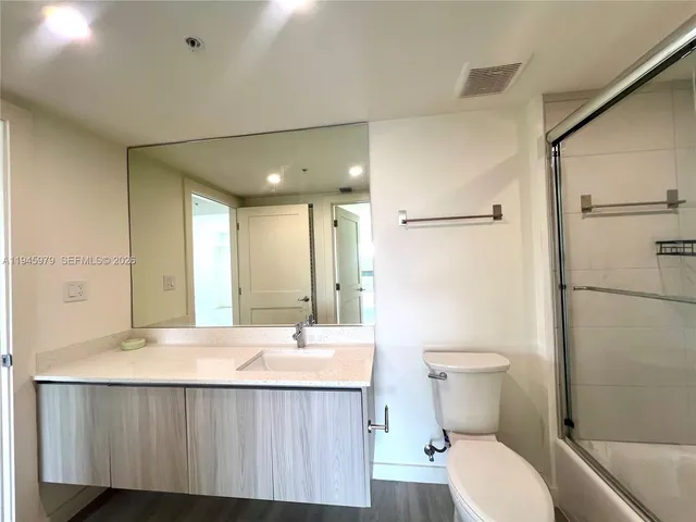 a bathroom with a sink a toilet a mirror and shower