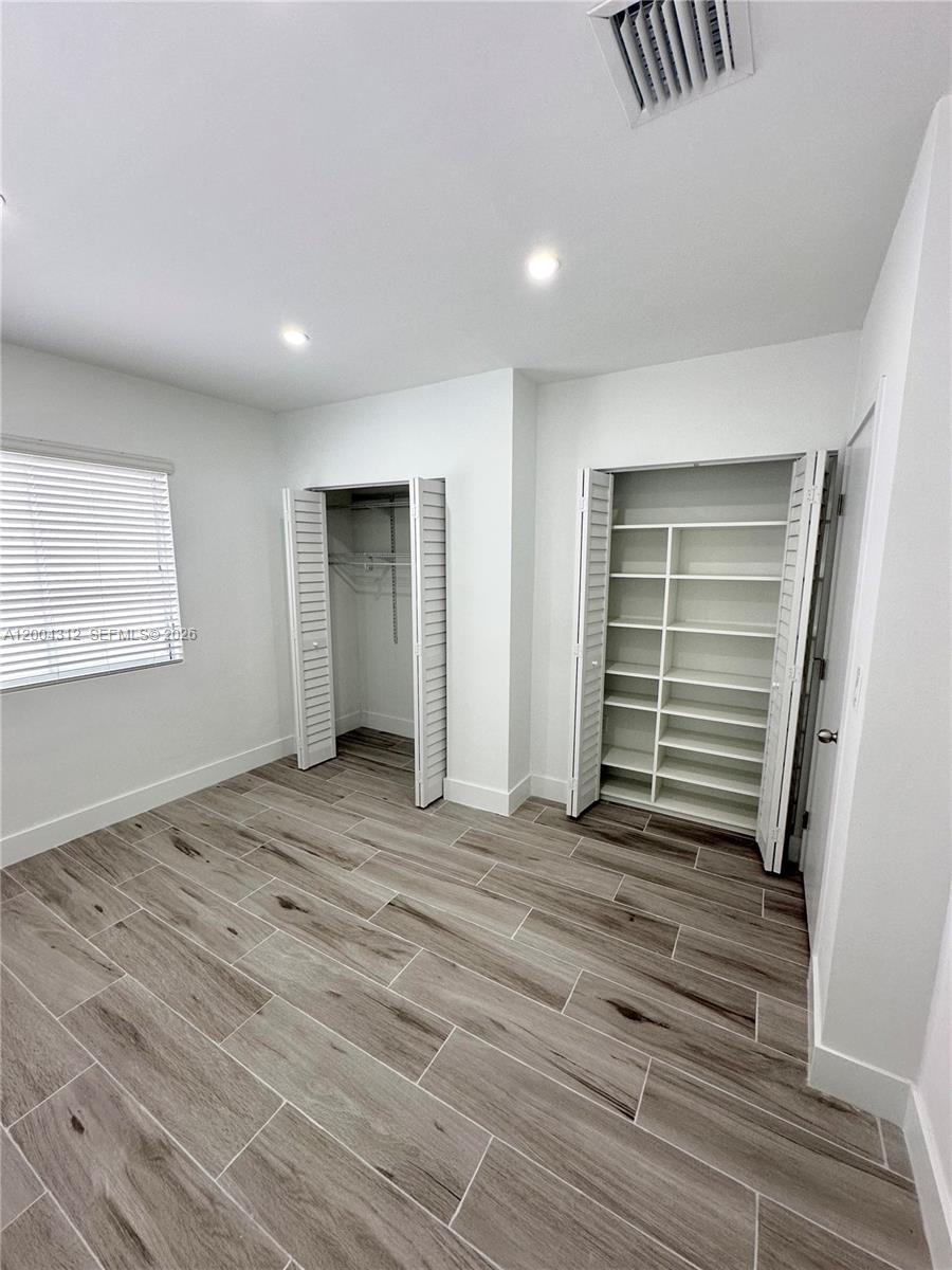 551 Southwest 57th Avenue, Unit 1 Miami, FL 33144 - Photo 17 of 24 a view of an empty room with wooden floor and a window