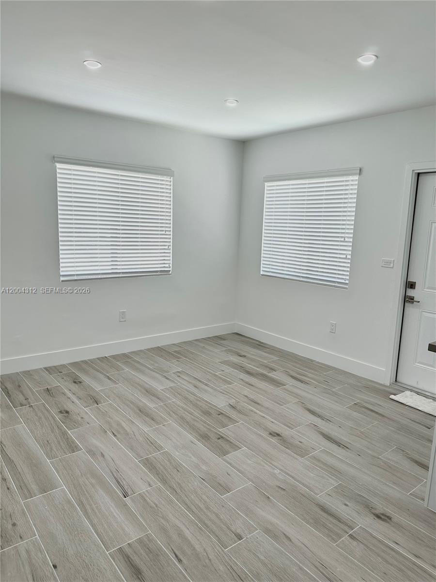 551 Southwest 57th Avenue, Unit 1 Miami, FL 33144 - Photo 4 of 24 an empty room with wooden floor and windows
