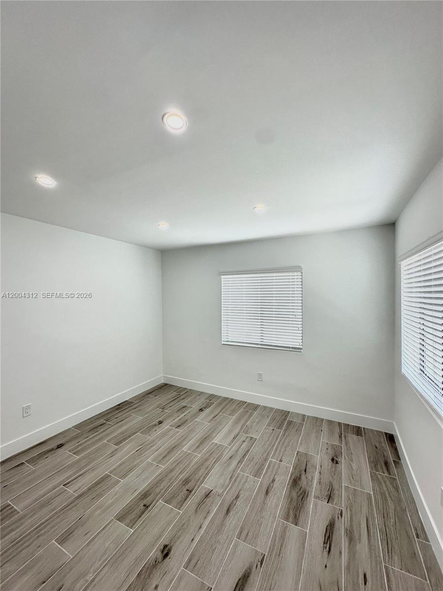 551 Southwest 57th Avenue, Unit 1 Miami, FL 33144 - Photo 5 of 24 an empty room with wooden floor and windows
