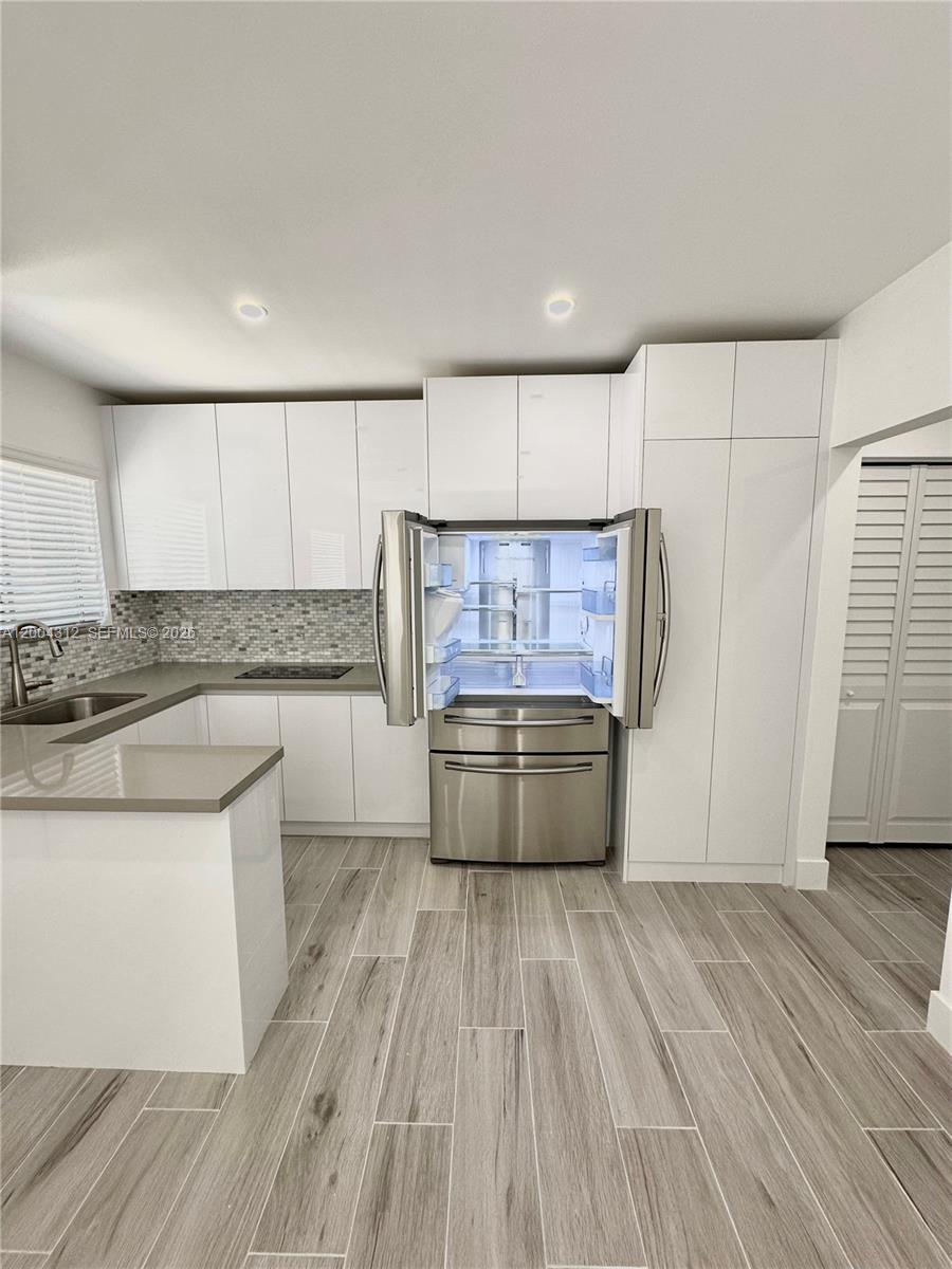 551 Southwest 57th Avenue, Unit 1 Miami, FL 33144 - Photo 10 of 24 a kitchen with stainless steel appliances wooden floors and wooden cabinets