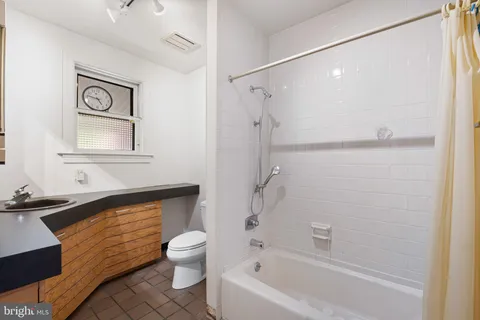 a bathroom with a granite countertop bathtub shower sink vanity and toilet