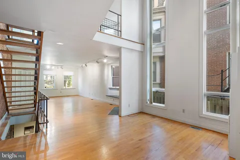 a view of a hallway with wooden floor and a living room