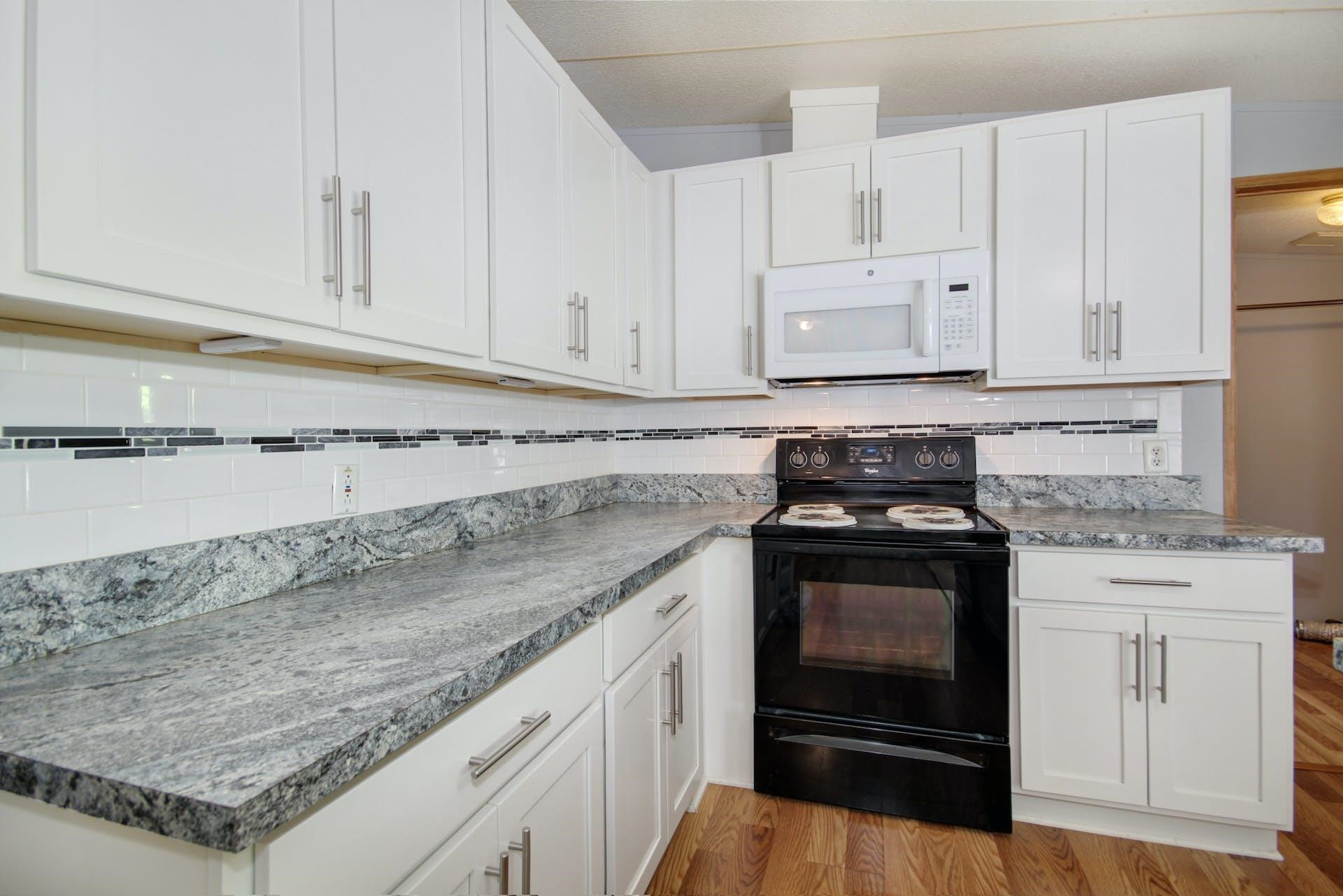 8144 Mt Pleasant Church Road Willow Spring, NC 27592 - Photo 11 of 25 a kitchen with granite countertop white cabinets and a stove