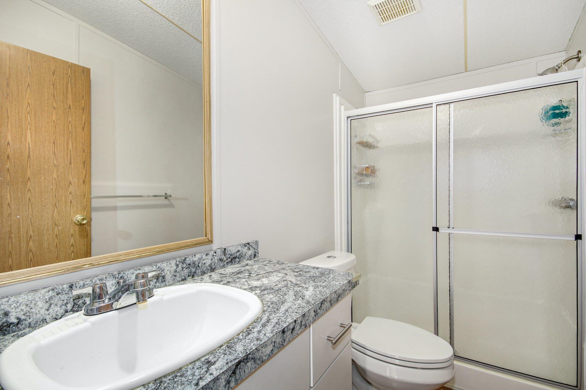 8144 Mt Pleasant Church Road Willow Spring, NC 27592 - Photo 19 of 25 a bathroom with a granite countertop sink toilet and shower