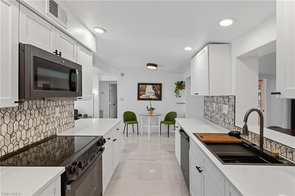 1280 Pine Street Naples, FL 34104 - Photo 11 of 36 a kitchen with granite countertop a sink and a stove top oven with wooden floor