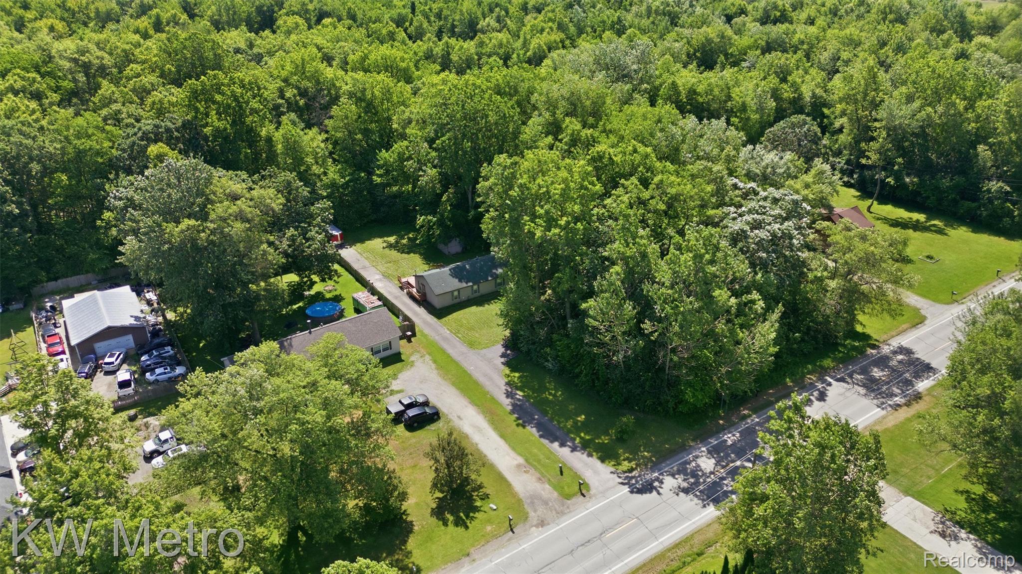 22733 Sumpter Road Belleville, MI 48111 - Photo 51 of 52 Spacious property featuring a large outbuilding with an overhead door, established trees, and direct road access