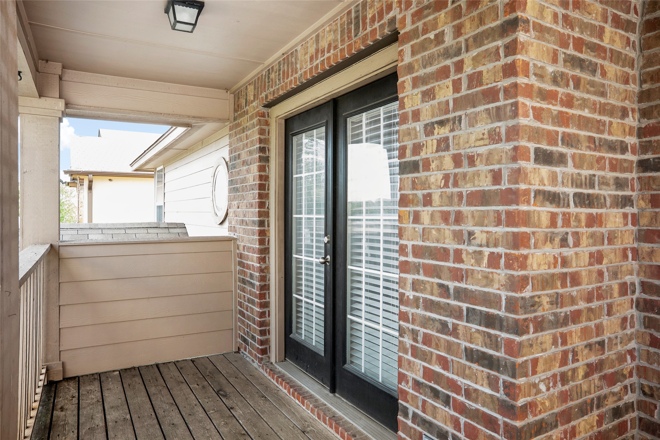 212 Foster Lane Jarrell, TX 76537 - Photo 12 of 22 Covered balcony featuring a wood railing, exterior lighting, and brick exterior accents over looks front yard