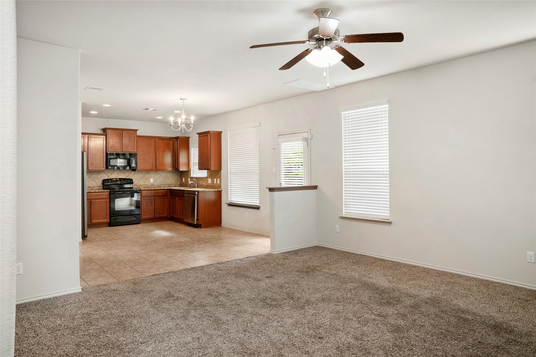 212 Foster Lane Jarrell, TX 76537 - Photo 4 of 22 Spacious living area featuring plush carpet flooring and a ceiling fan with integrated lighting, and windows throughout providing natural light