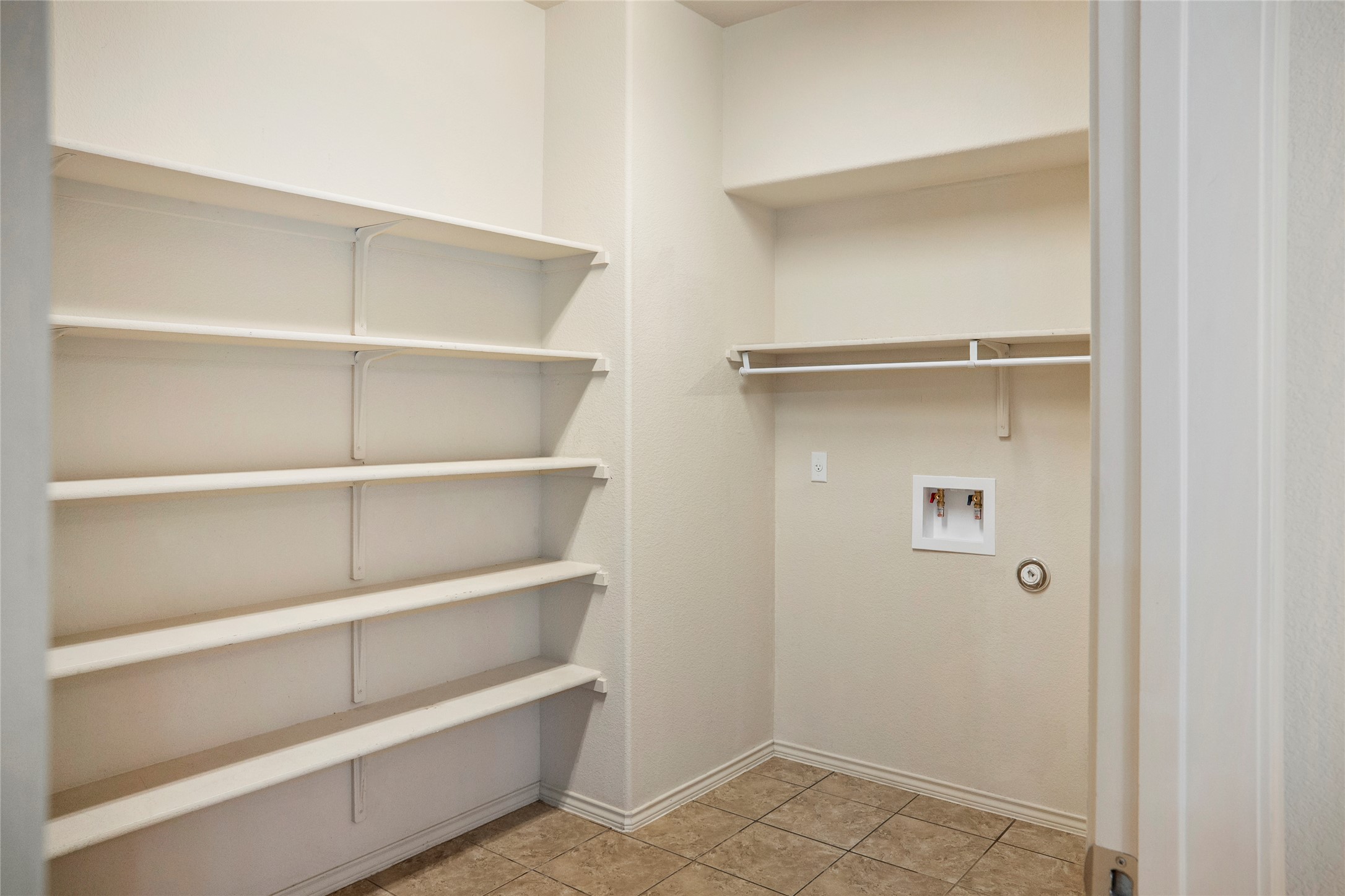 212 Foster Lane Jarrell, TX 76537 - Photo 8 of 22 Utility and pantry space featuring extensive shelving, a clothes hanging rod, and tile flooring
