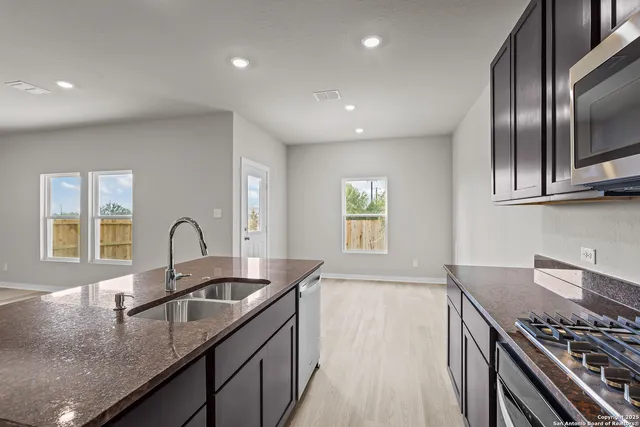 a kitchen with granite countertop stainless steel appliances a sink stove and cabinets