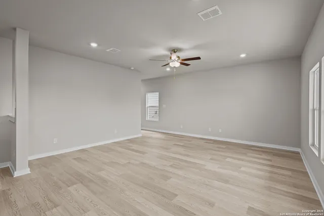 a view of an empty room with a chandelier fan