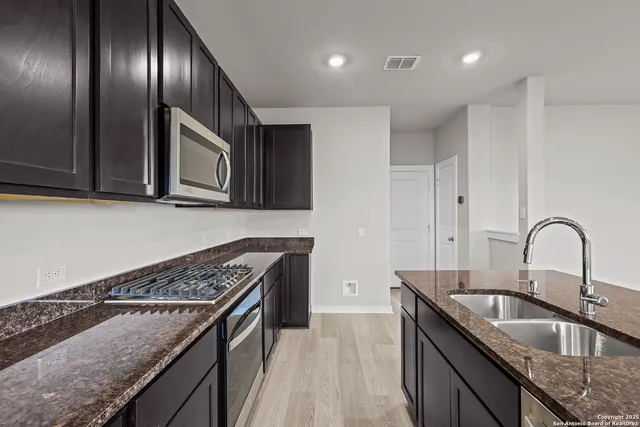 a kitchen with granite countertop stainless steel appliances a sink stove top oven and cabinets