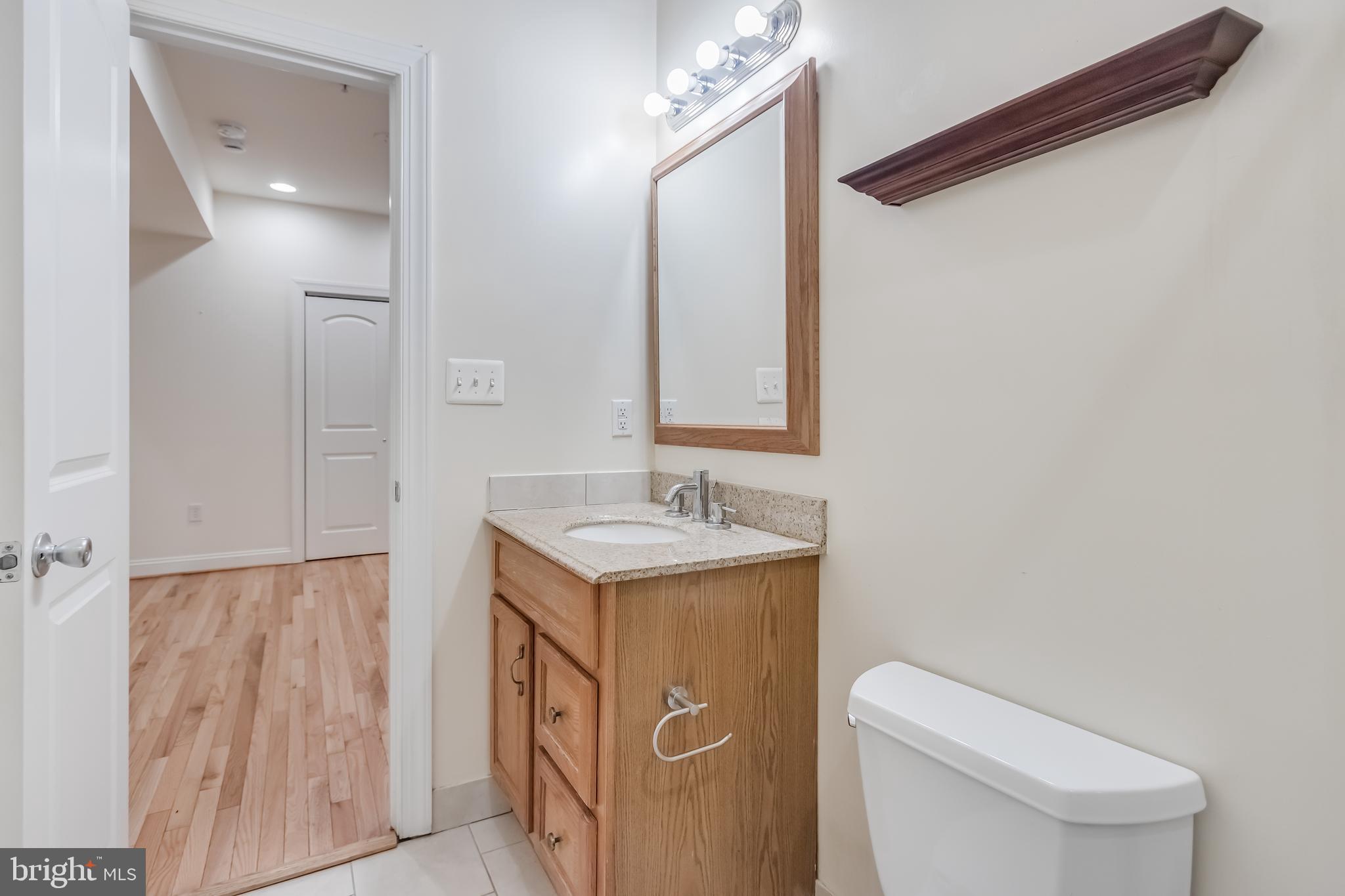 2307 18th Street Northwest, Unit 1 Washington, DC 20009 - Photo 21 of 21 a bathroom with a granite countertop sink a toilet and a mirror