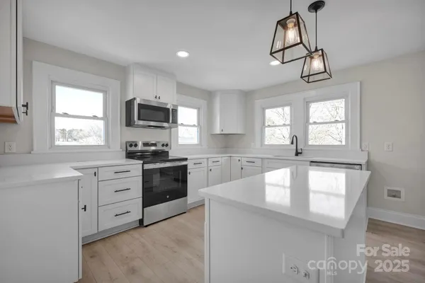 a kitchen with granite countertop a stove a sink a window and a refrigerator