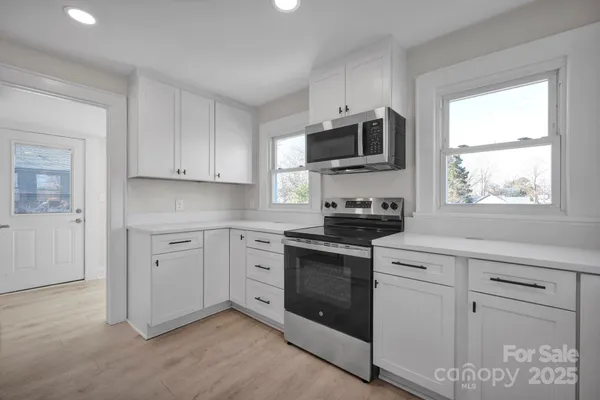 a kitchen with white cabinets stainless steel appliances and window