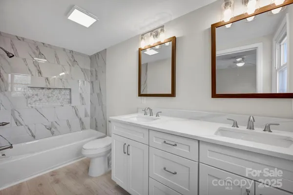 a bathroom with a toilet a sink a tub and mirror
