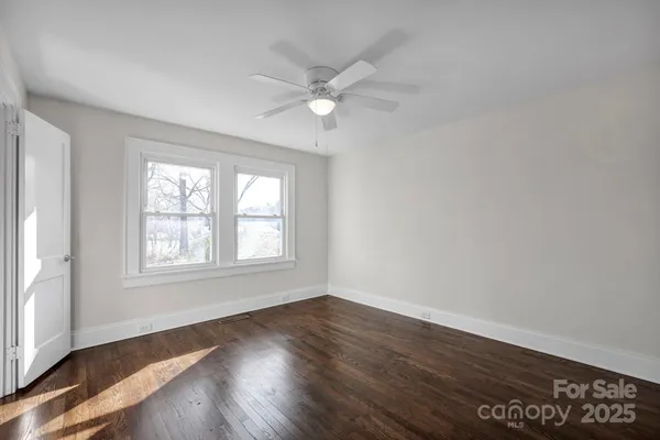 an empty room with wooden floor fan and windows