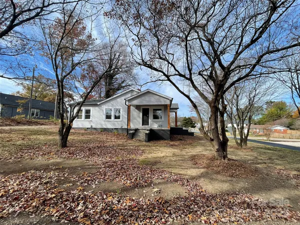 a backyard of a house with large trees and barbeque oven