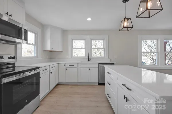 a kitchen with white cabinets and chandelier