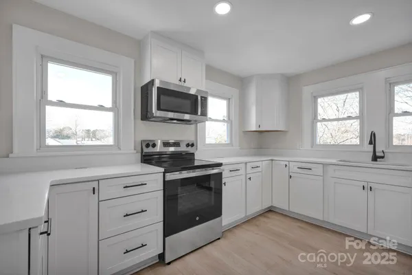 a kitchen with white cabinets appliances and window