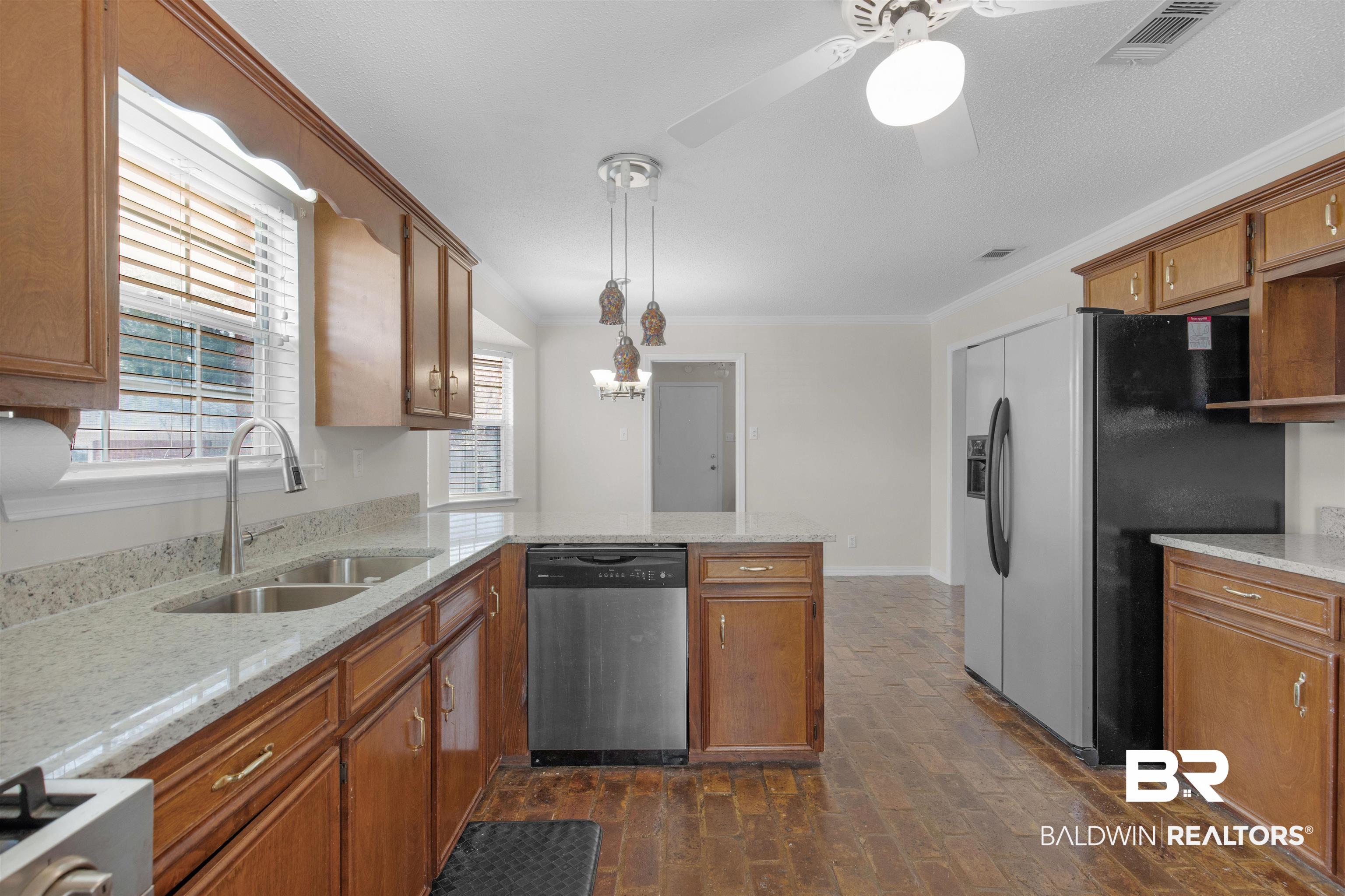 7225 Smithfield Road East Mobile, AL 36695 - Photo 5 of 27 Kitchen featuring a sink, stainless steel appliances, a peninsula, brown cabinetry, and crown molding
