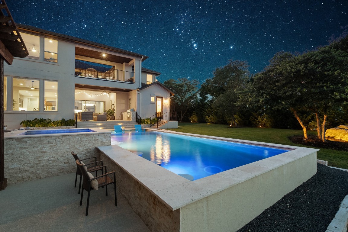 a view of swimming pool with outdoor seating and trees in the background