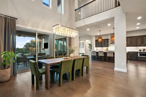 a kitchen with stainless steel appliances kitchen island granite countertop a stove a sink a oven a dining table and chairs with wooden floor