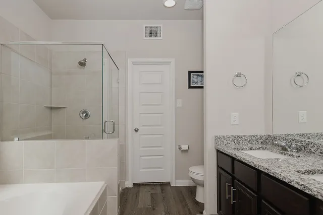a bathroom with a granite countertop sink a toilet and shower