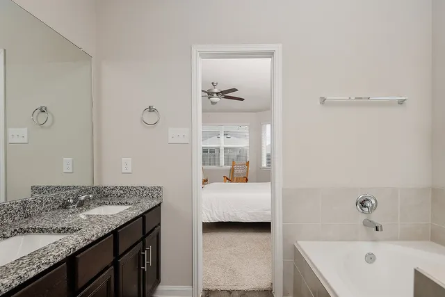 a en suite bathroom with a granite countertop sink and a bathtub