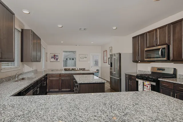 a kitchen with stainless steel appliances granite countertop a sink stove and refrigerator