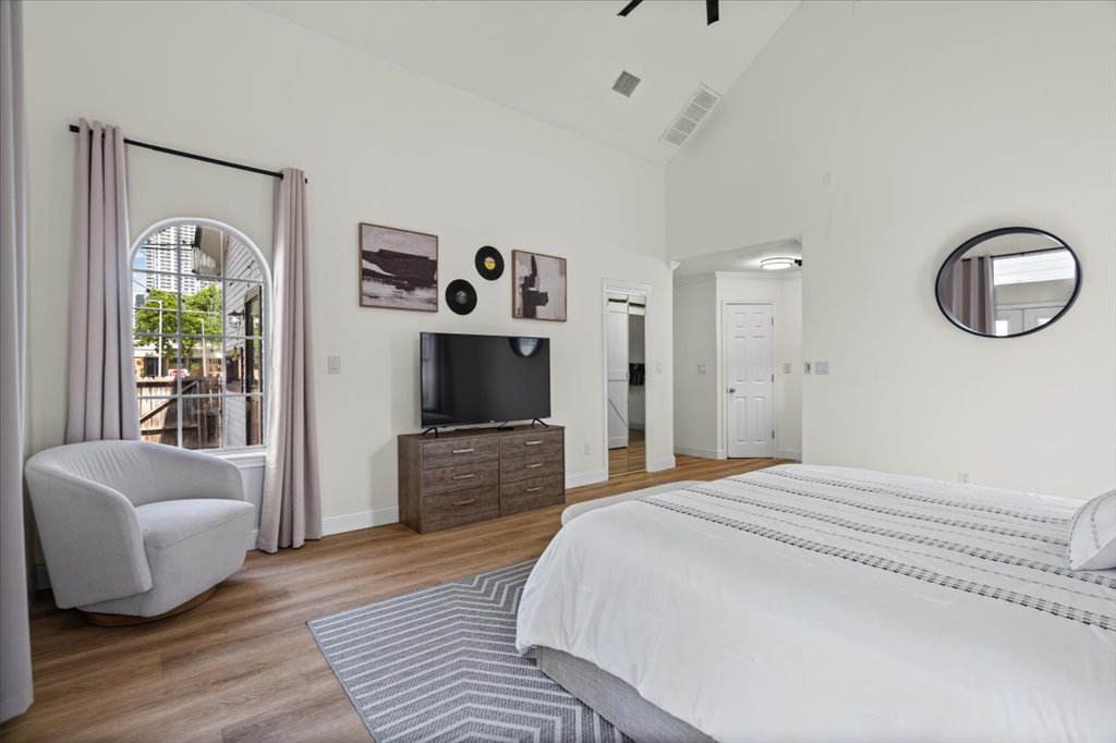 1201 Garden Street, Unit A Austin, TX 78702 - Photo 15 of 30 Vaulted ceiling bedroom with an arched window, wood-finish flooring, and a built-in media console