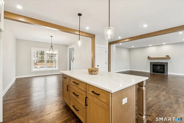 a kitchen with stainless steel appliances kitchen island granite countertop a refrigerator a sink a stove and white cabinets with wooden floor