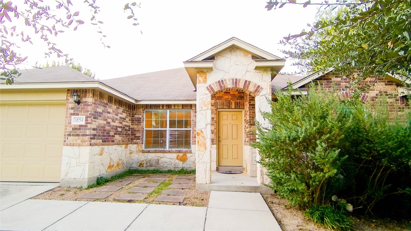 Property entrance with stone siding, an attached garage, and brick siding