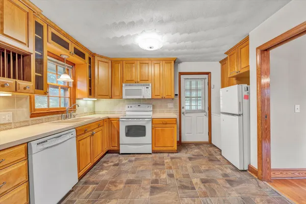 a large kitchen with granite countertop a stove a sink dishwasher a refrigerator and cabinets
