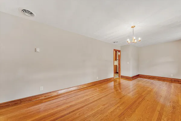a view of an empty room with wooden floor and a ceiling fan