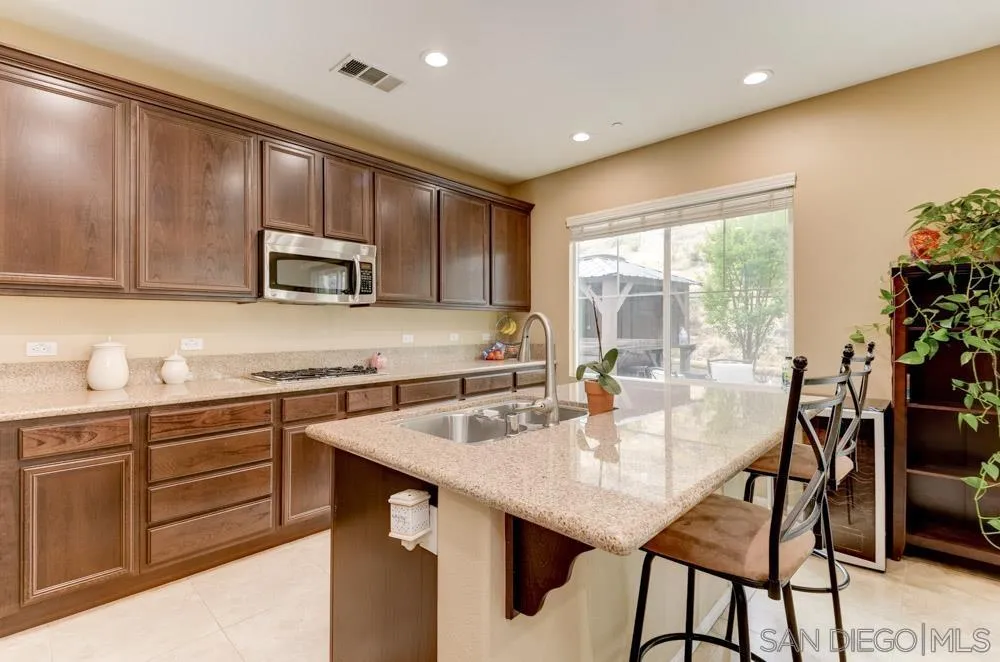1145 Los Senderos Drive Santee, CA 92071 - Photo 9 of 30 a kitchen with a table chairs microwave and cabinets