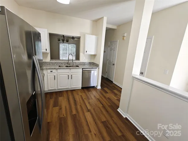 a kitchen with sink a refrigerator and wooden floor