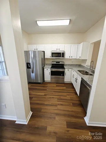 a kitchen with stainless steel appliances a refrigerator sink and wooden floor