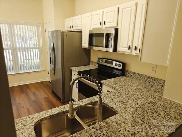 a kitchen with stainless steel appliances granite countertop a sink a stove and a refrigerator