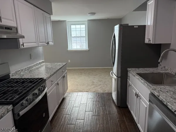 a kitchen with granite countertop a refrigerator stove and sink
