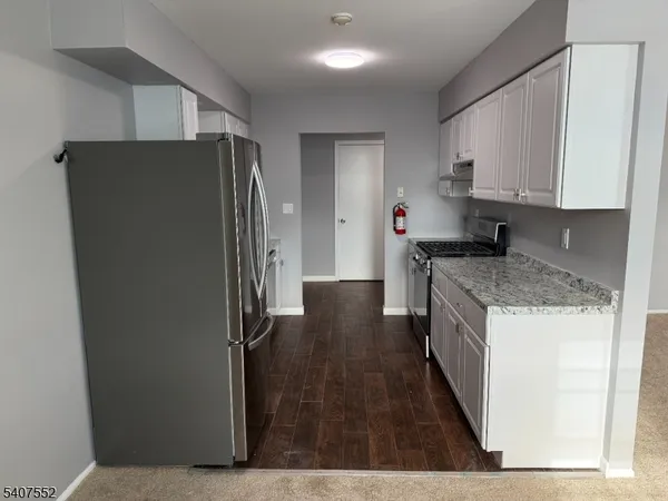 a kitchen with granite countertop a refrigerator and a stove top oven