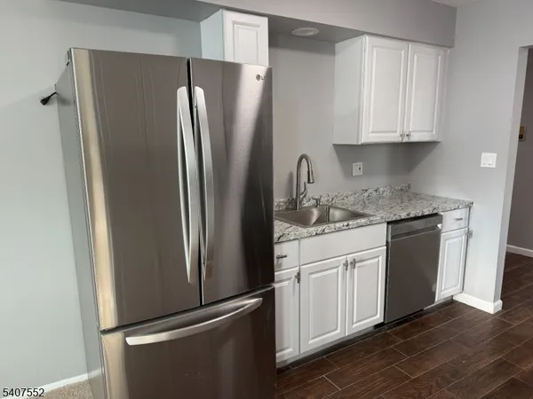 a kitchen with stainless steel appliances granite countertop a refrigerator and white cabinets