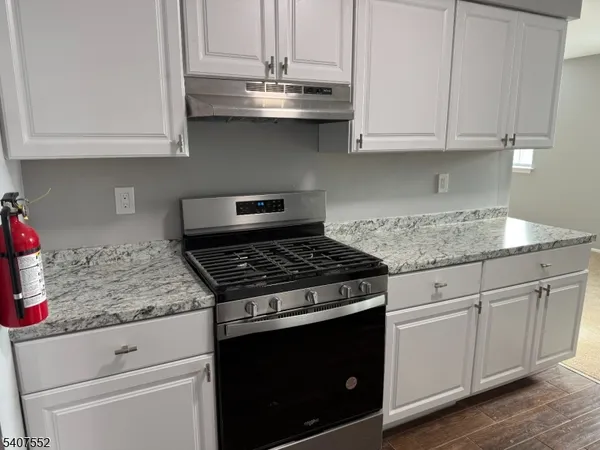 a kitchen with granite countertop white cabinets and a stove