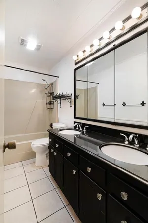 a bathroom with a double vanity sink and mirror with toilet