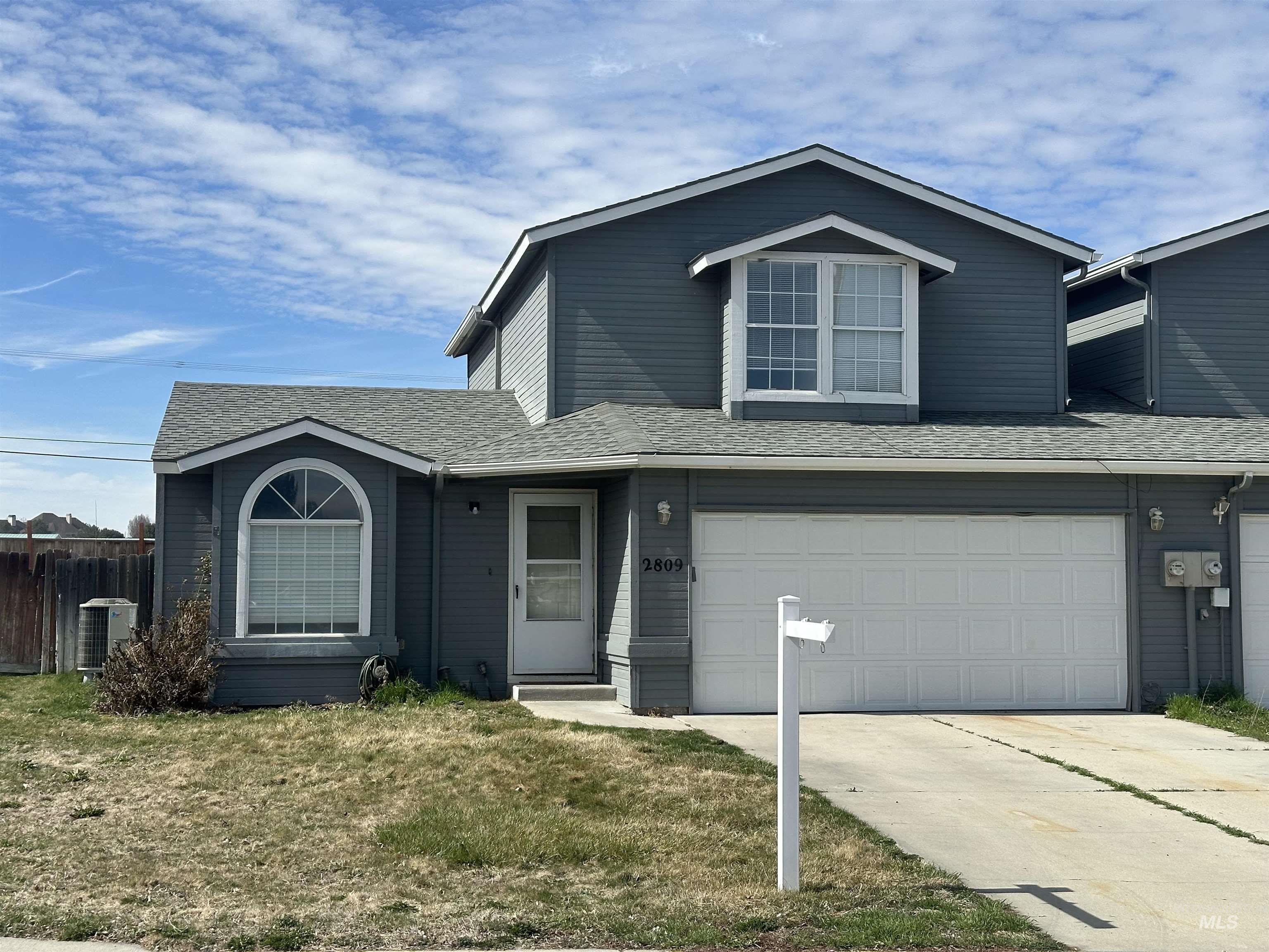 Traditional-style house featuring a shingled roof, driveway, and a garage