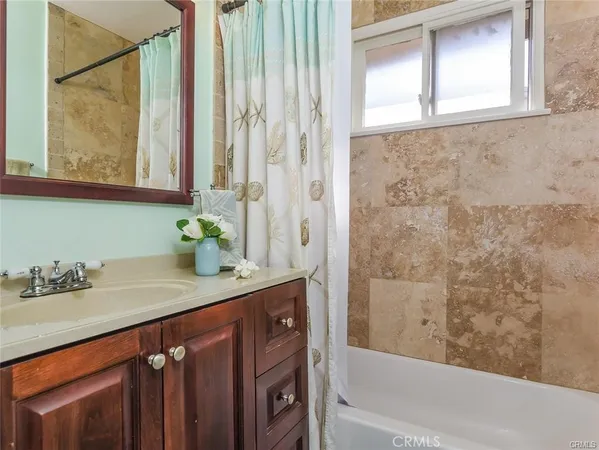 a bathroom with a granite countertop sink a mirror and a bathtub