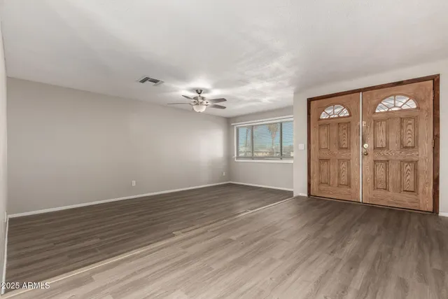 a view of an empty room with wooden floor and a window