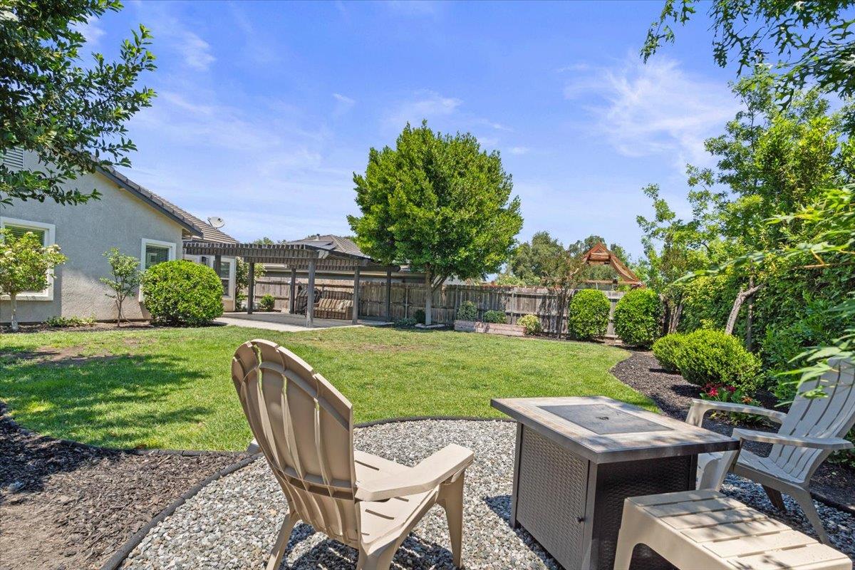 437 Silver Ridge Court Oakdale, CA 95361 - Photo 30 of 41 a view of a backyard with table and chairs potted plants and a large tree