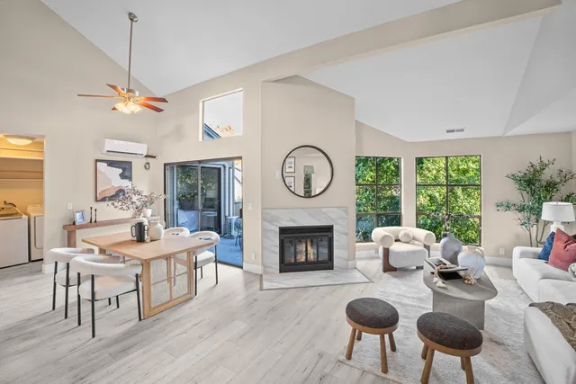 a living room with furniture a fireplace a clock and a large window